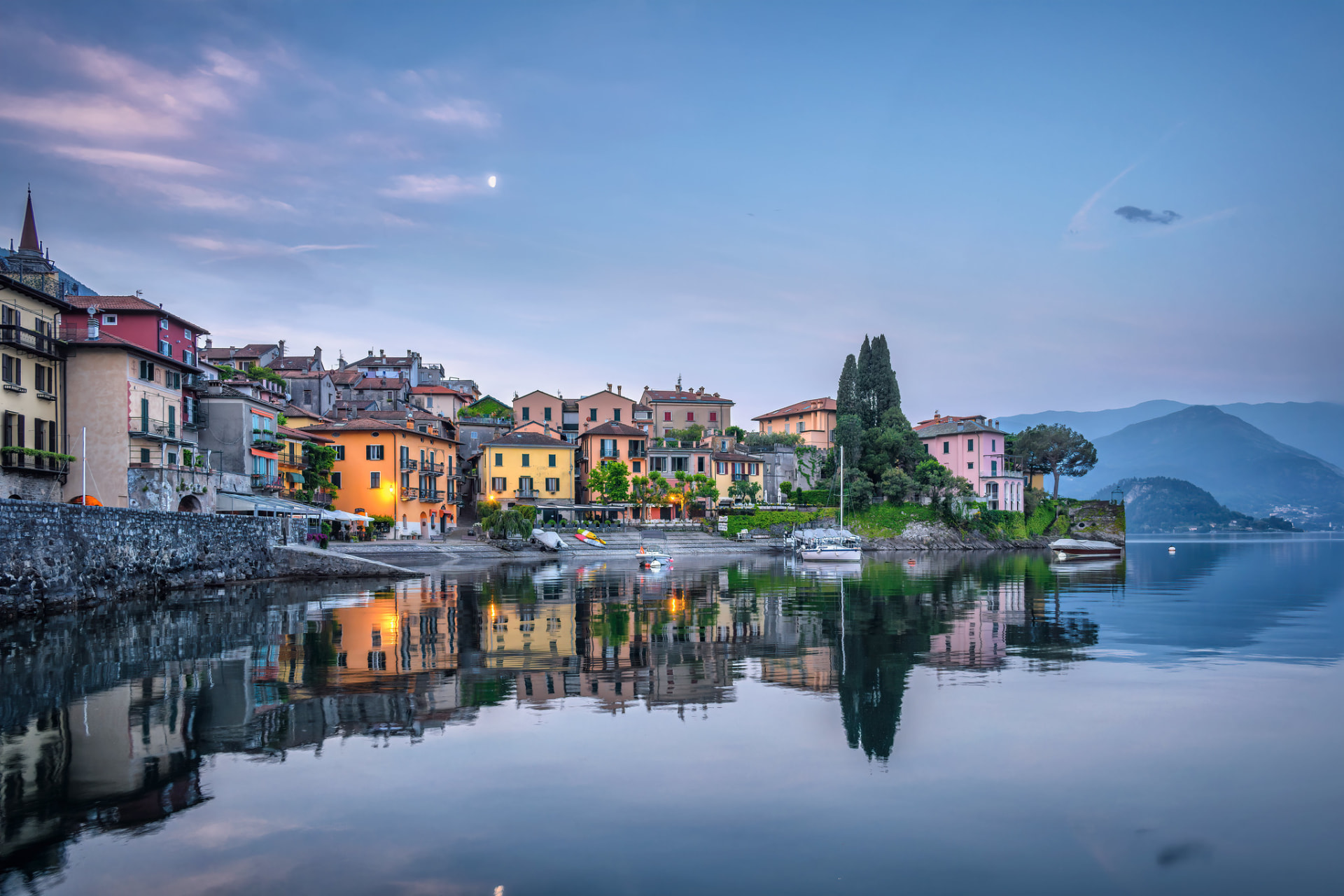Varenna's pastel waterfront buildings and moored boats reflected in calm water at dusk