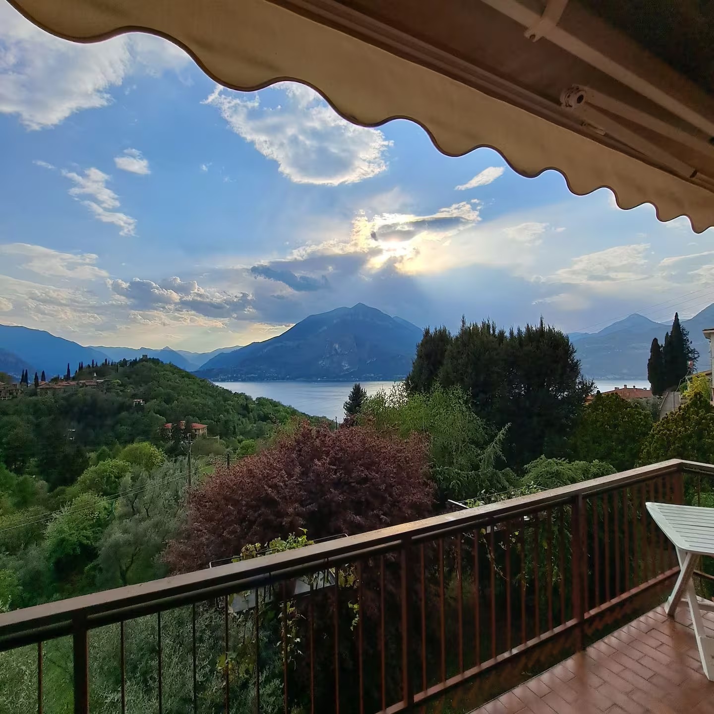 View from the balcony over the hills and Lake Como as sunbeams break through the clouds