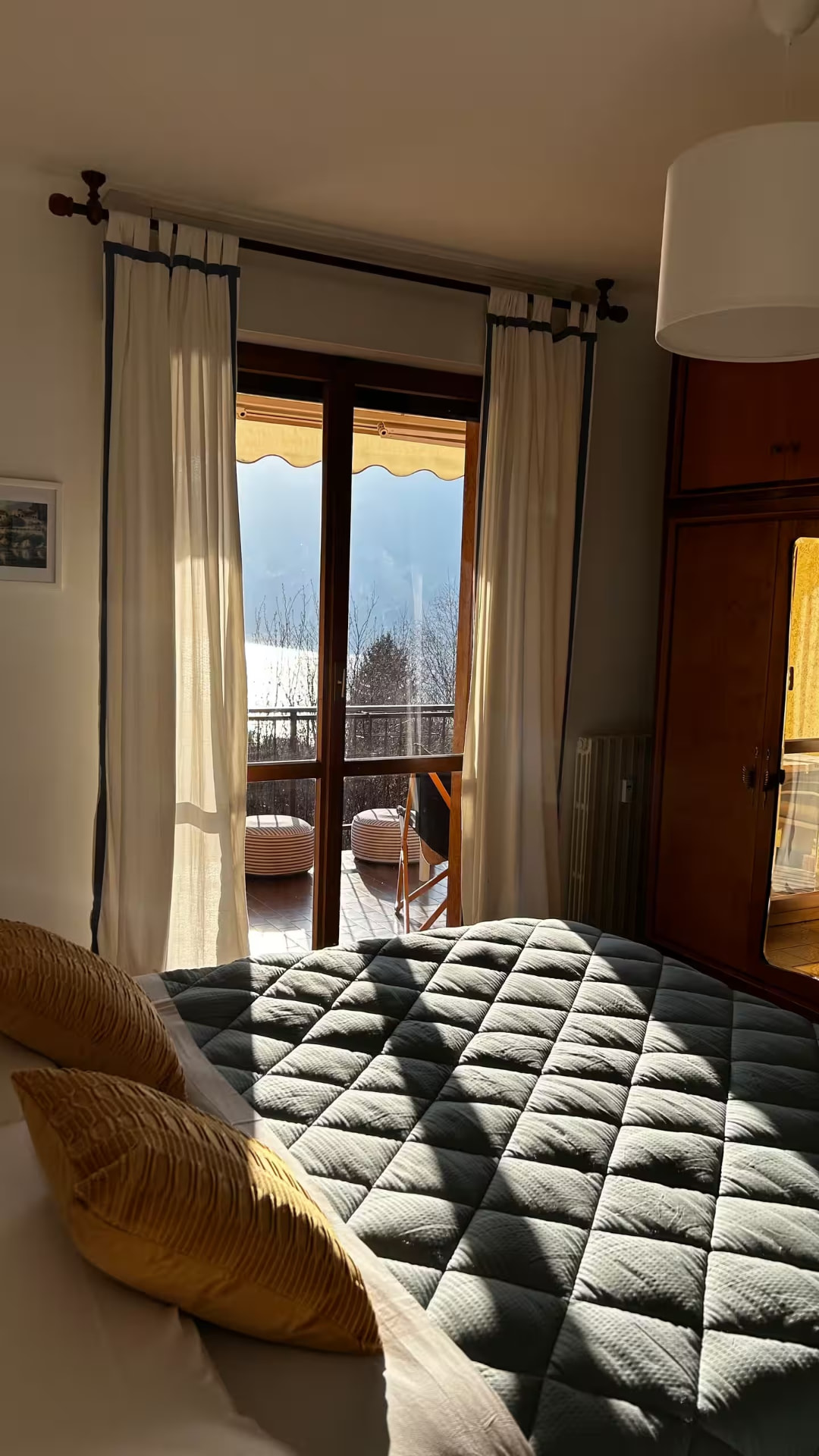 Bedroom with glass doors onto the balcony, lake and mountains beyond