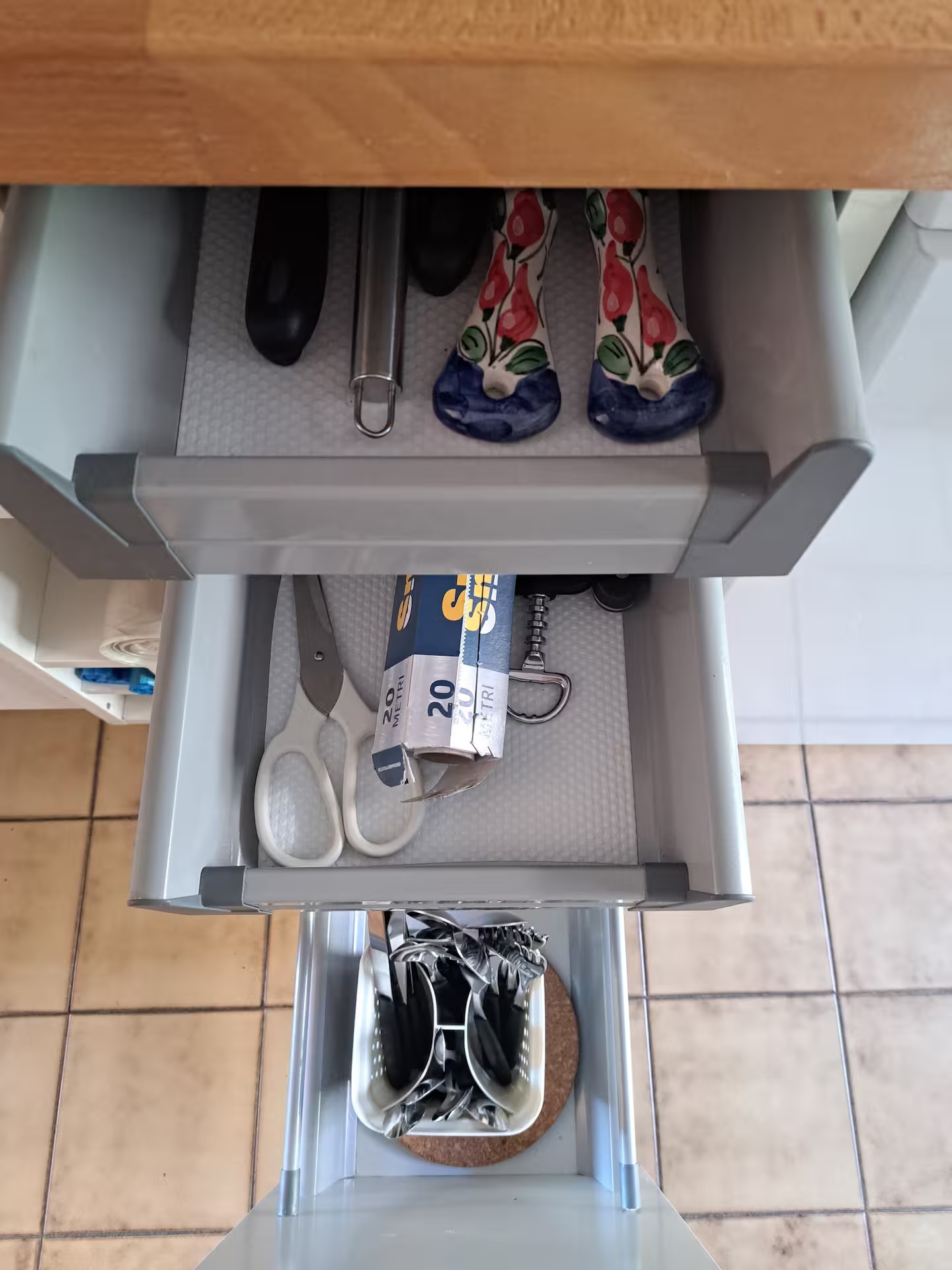Open kitchen drawers with cooking utensils, corkscrew and cutlery